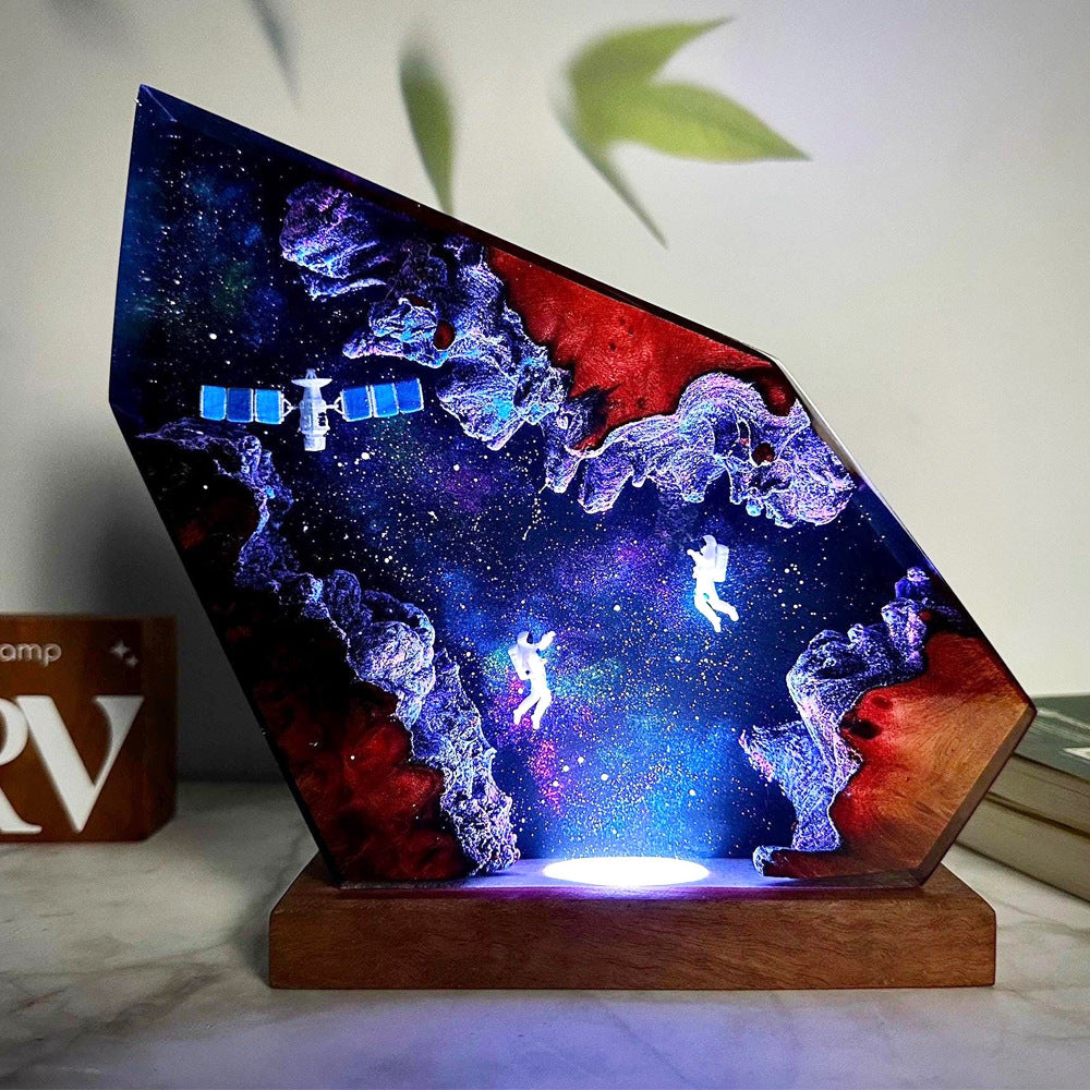Orbit Lamp — an astronaut and a satellite suspended in a resin nebula on a wood base, lit from below
