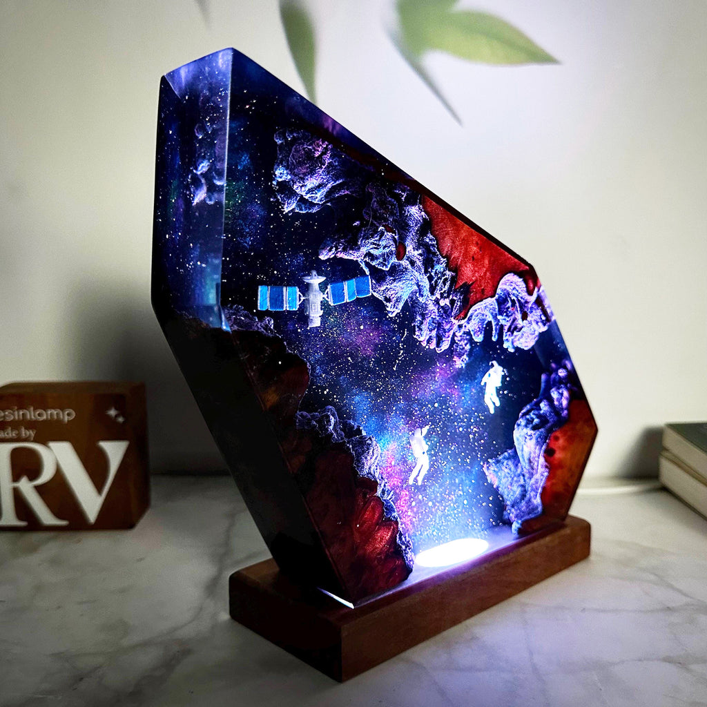 Orbit Lamp — an astronaut and a satellite suspended in a resin nebula on a wood base, lit from below