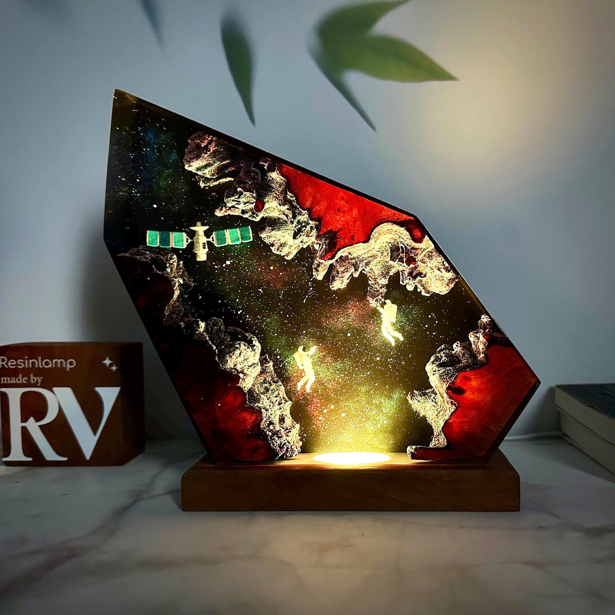 Orbit Lamp — an astronaut and a satellite suspended in a resin nebula on a wood base, lit from below
