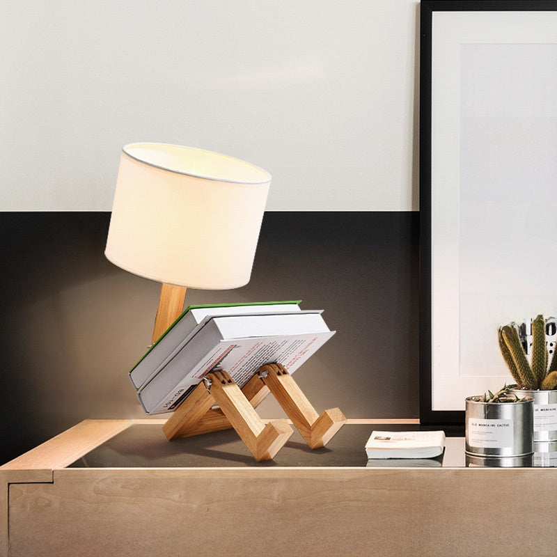 Robot Lamp — a jointed wooden figure sitting with its legs out, holding a fabric lampshade overhead